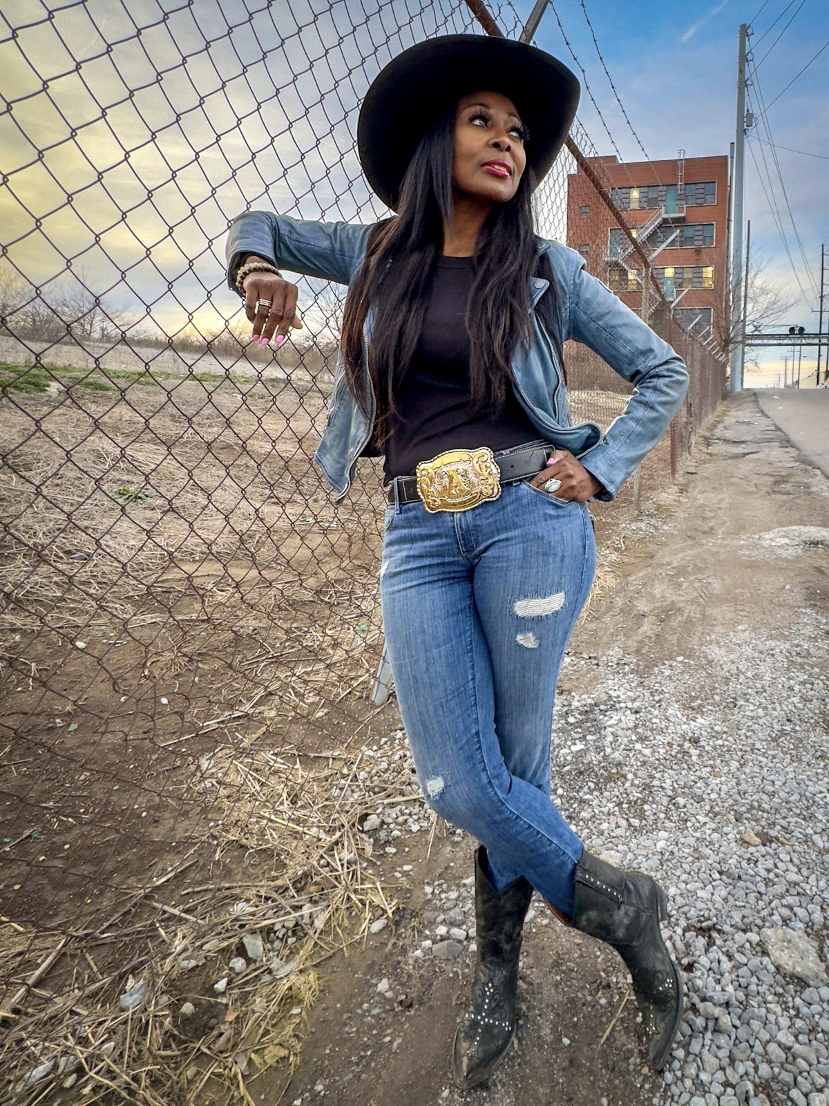 Brei Carter — denim and buckle, leaning on a rail fence